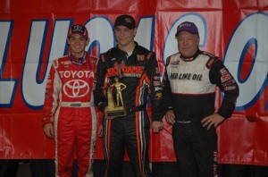 Kevin Swindell holds his third Golden Driller trophy in a row for winning Saturday's Chili Bowl Nationals A-Main.  Swindell is flanked by second and third place drivers Sammy Swindell and Kyle Larson. - Alan Holland Photo