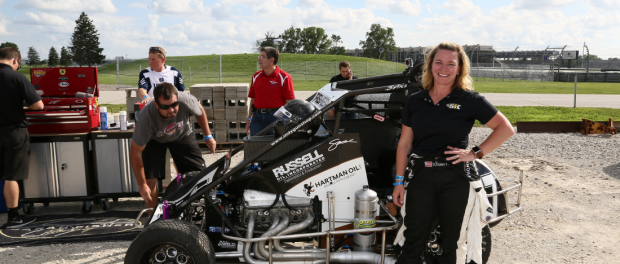 Sarah Fisher posing with her car at the Indianapolis Motor Speedway for the dirt oval exhibition with Tony Stewart. (Chris Jones/IMS Image)