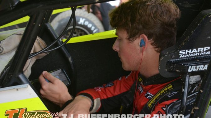Bryce Lucius watching cars qualify on his phone before going out for his own qualifying effort Friday at Eldora Speedway. (T.J. Buffenbarger Photo)